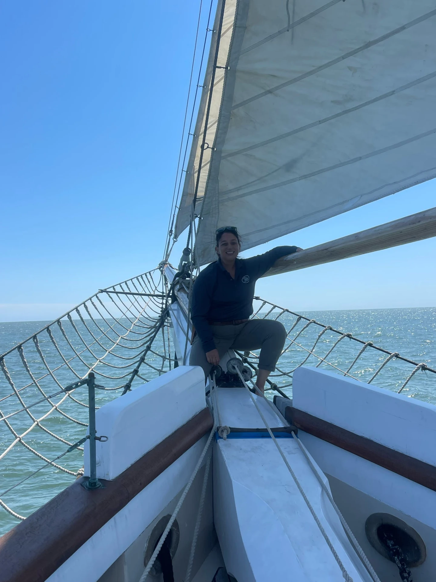 A Maritime Gal leaning on the bow rail of a tall ship under full sail
