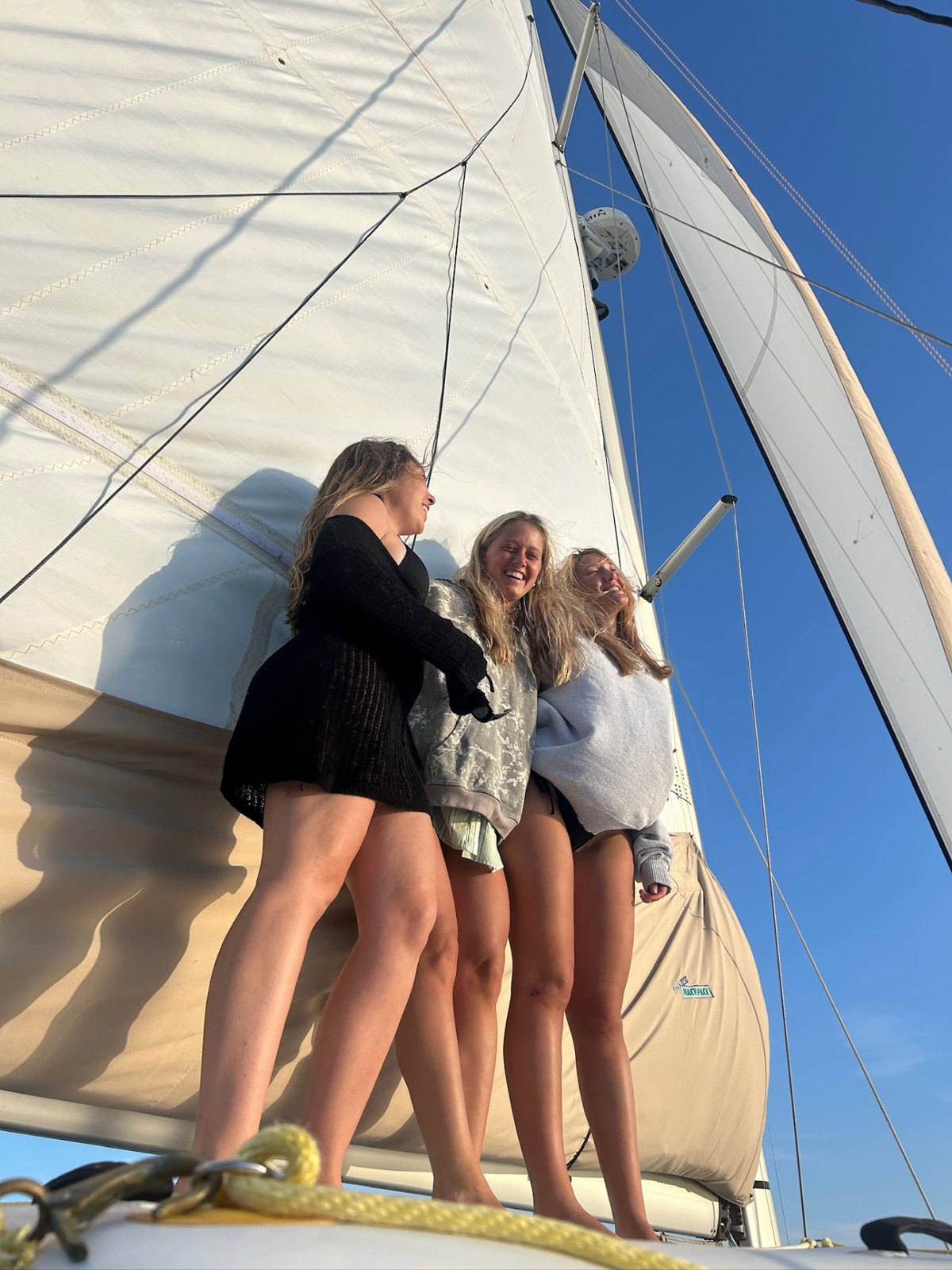 Three Charleston Maritime Gals laughing on the foredeck under full sail