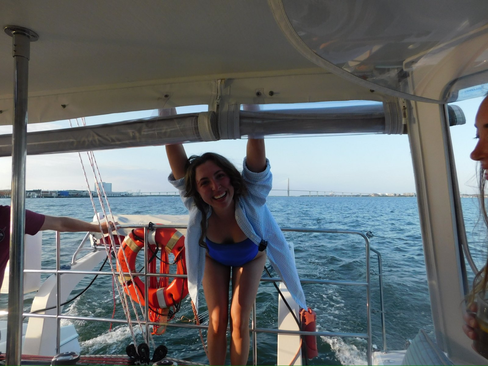 A gal laughing under the bimini with the Ravenel Bridge behind her