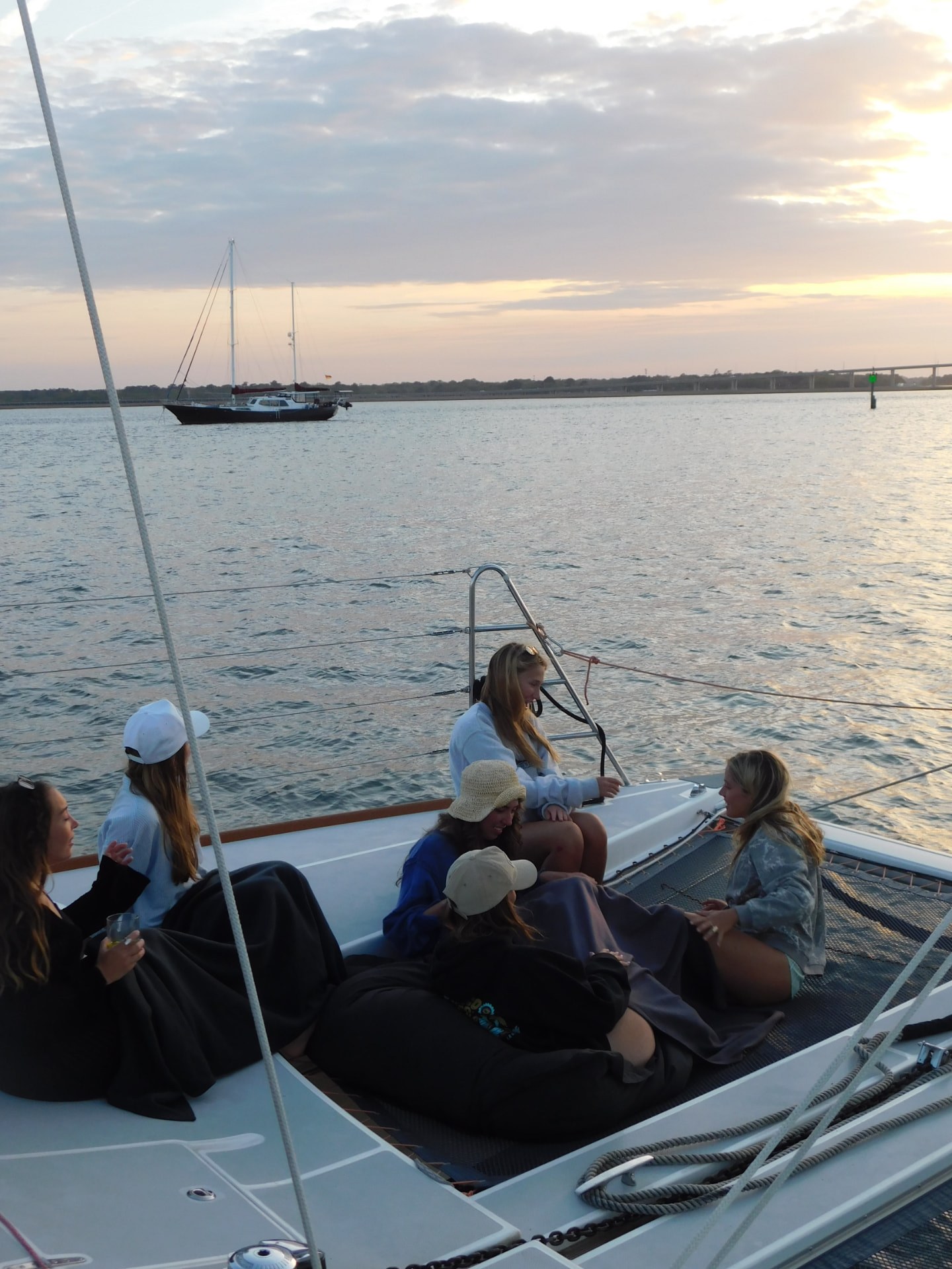 Maritime Gals gathered on the deck of a sailboat at sunset in Charleston harbor