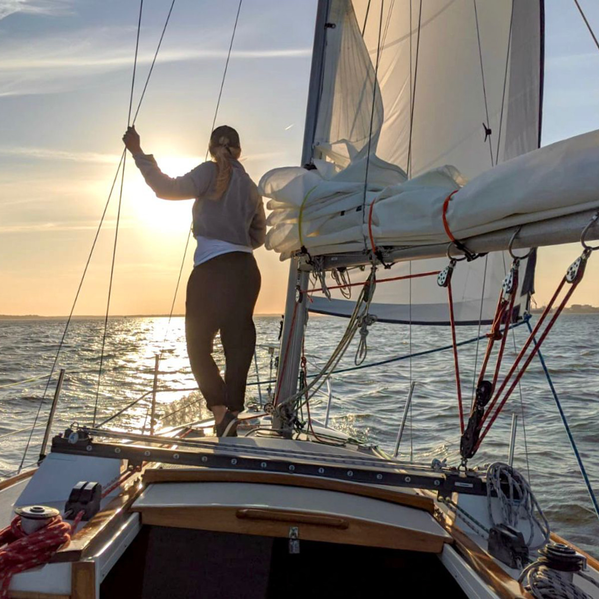 A sailor standing on the foredeck at sunset in Charleston Harbor