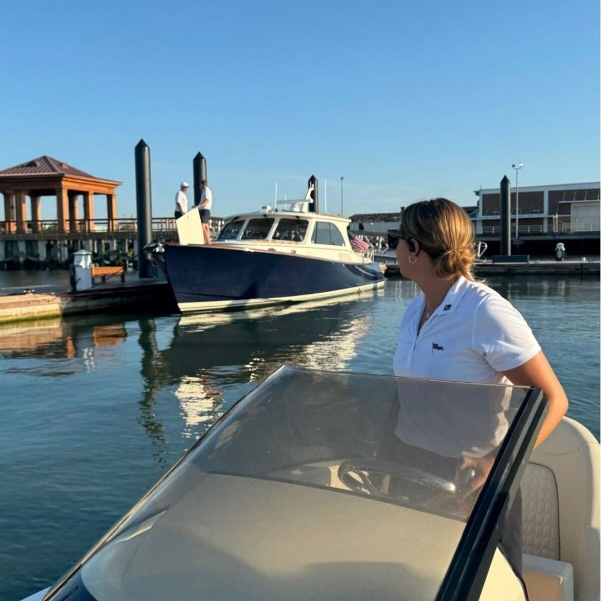 A Maritime Gal at the helm cruising past the marina on a bluebird morning