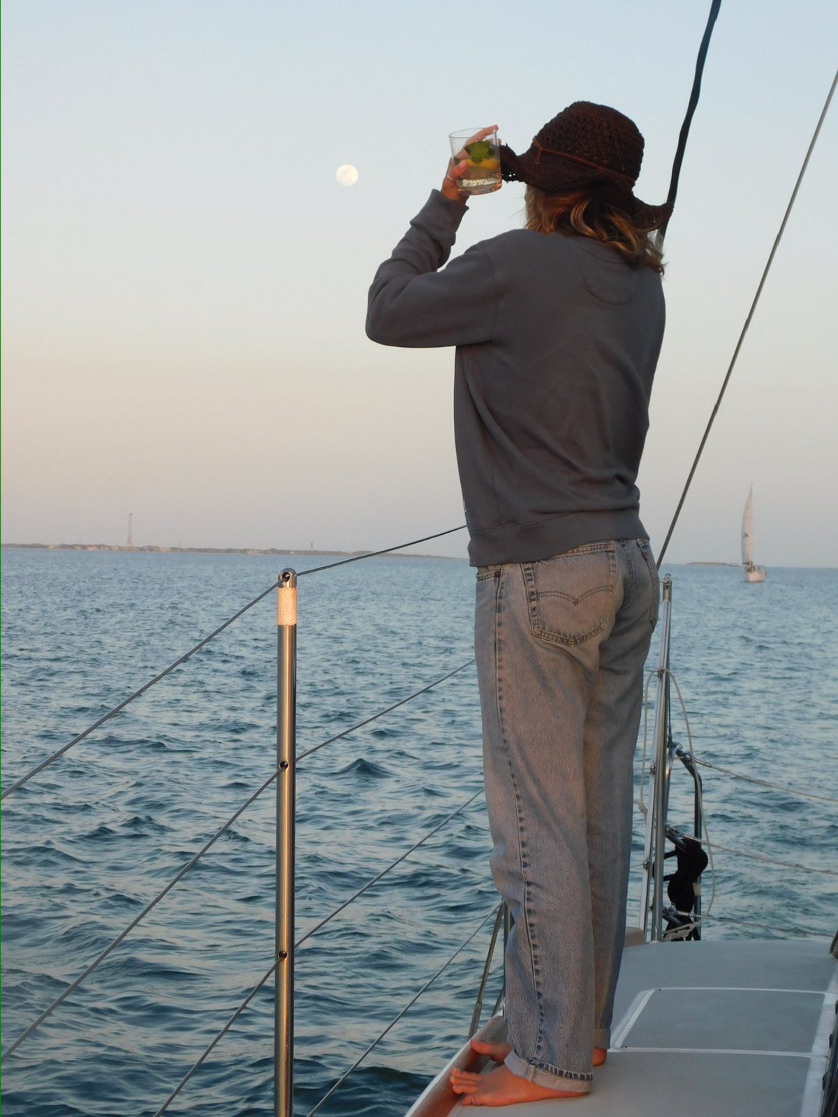 A sailor watching the moon rise from the rail underway