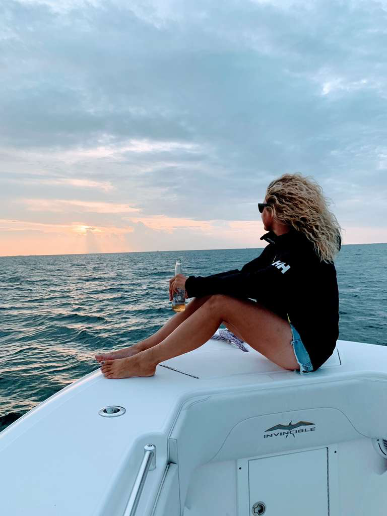 A Maritime Gal relaxing on the bow at sunset with the harbor behind her